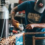 Man sawing metal in manufacturing factory.